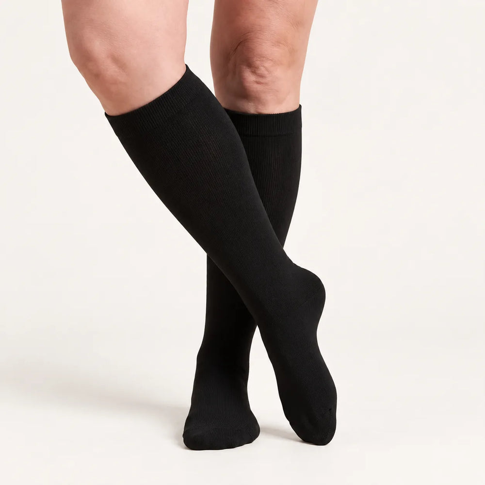 Lovelle Lift compression socks in Black – knee-high, legs crossed